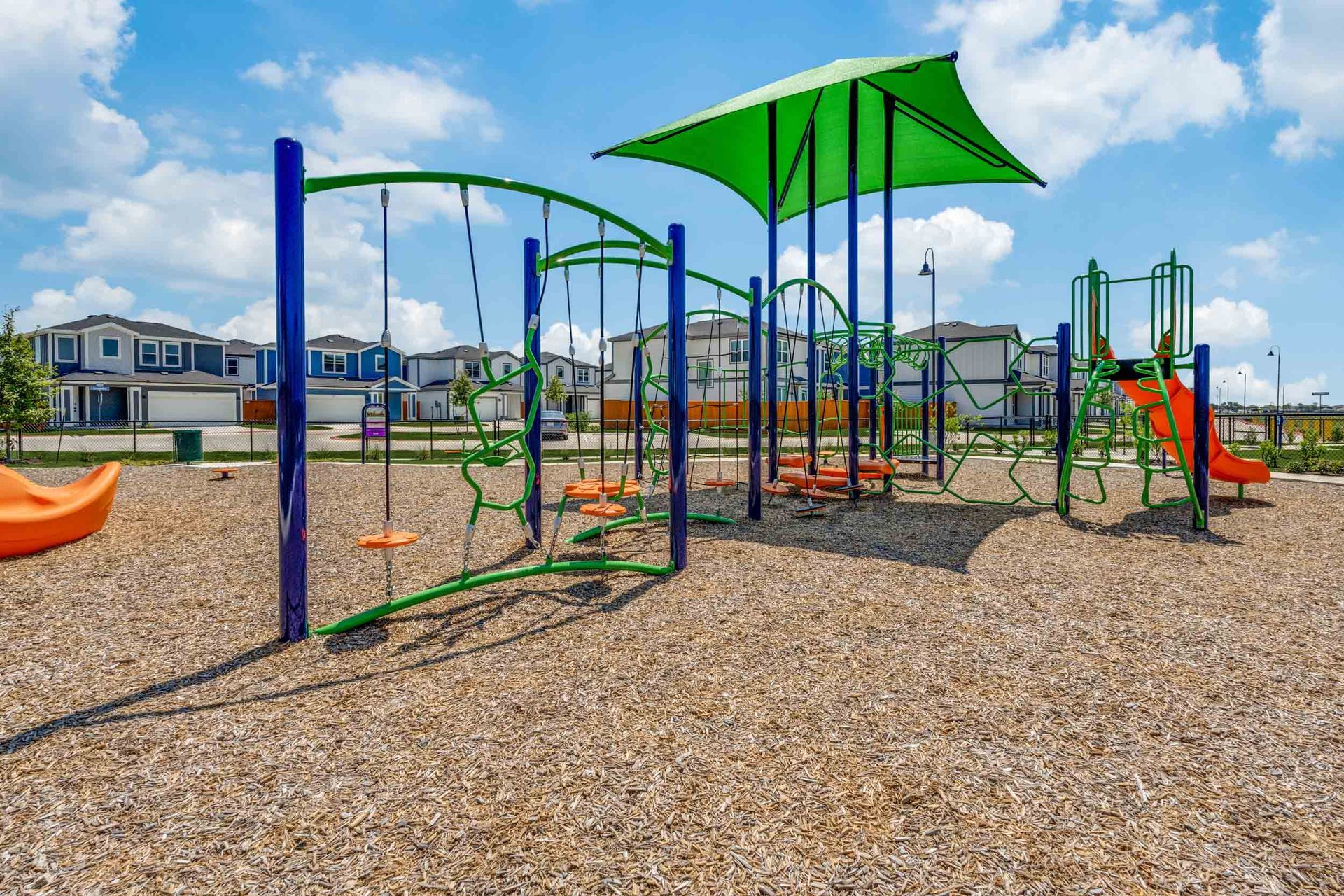 Playground equipment with swings and slides under a sunshade