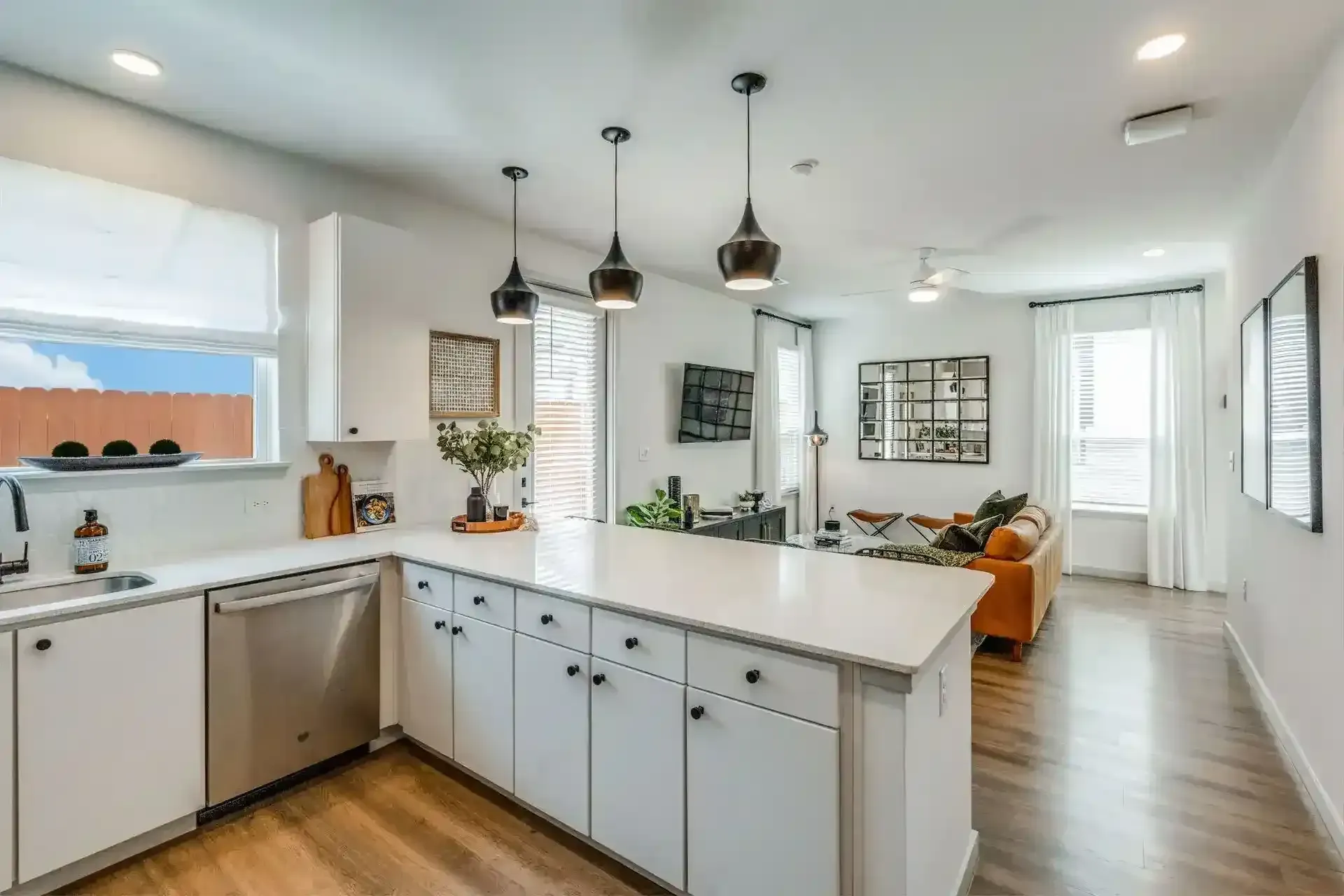 Modern kitchen with white cabinets and living area in background.