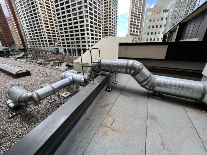 Rooftop view with ventilation pipes; tall buildings in the background.