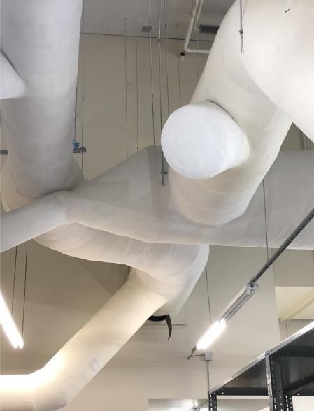 White, cloth-covered structures, perhaps ventilation, hang from a ceiling in a room with fluorescent lights.