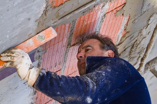 A man is plastering a wall with a level.