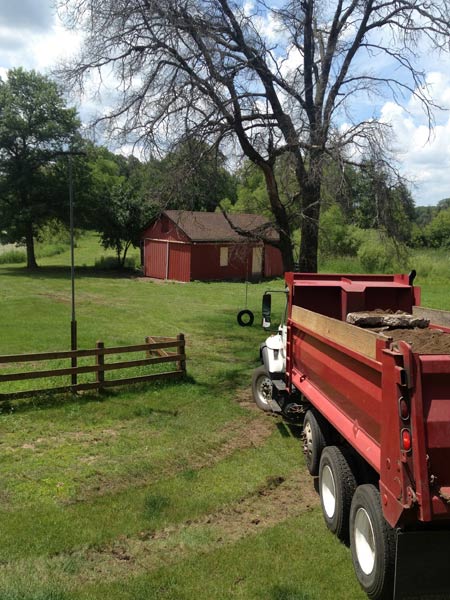 Red truck in a grassy place — Cedar, MN — Casper's Excavating