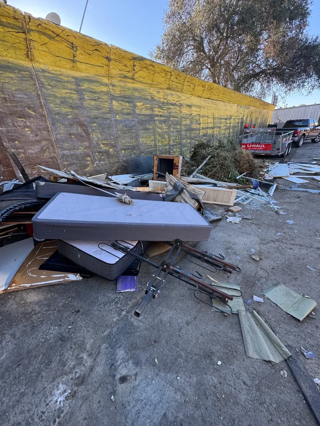 A pile of trash is sitting on the ground in front of a yellow wall.