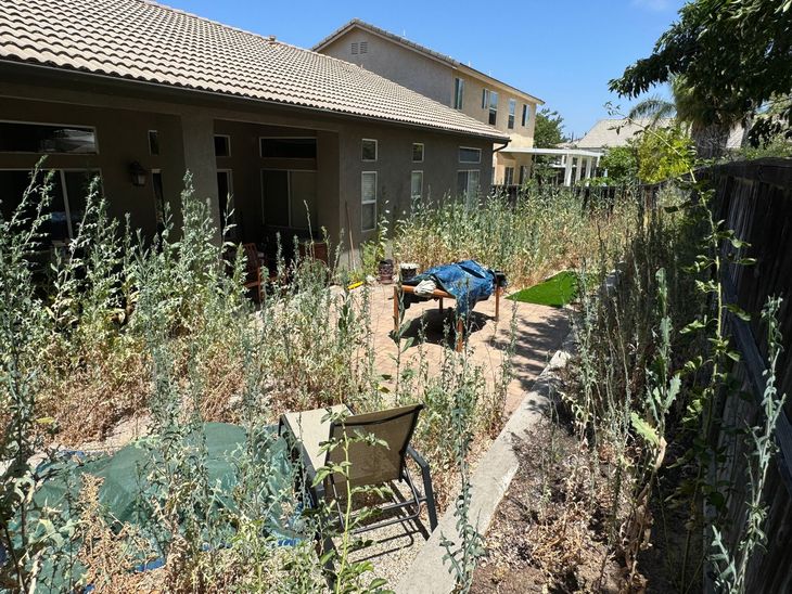 There is a table and chairs in the backyard of a house.
