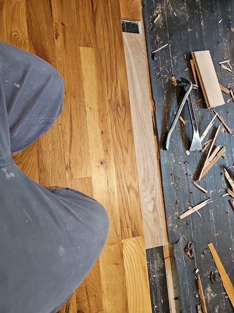 A person is working on a wooden floor with a spatula for flooring repairs in san diego county