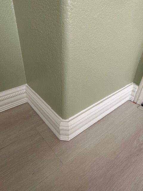 A corner baseboard in carlsbad of a room with green walls and white trim.