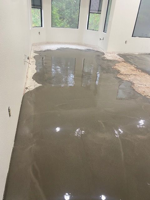 A room with a lot of concrete on the floor and a lot of windows.