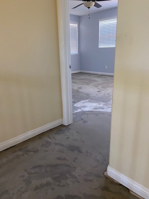 A hallway leading to a bedroom with a ceiling fan.