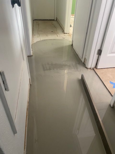 A hallway with a white tile floor and white doors.