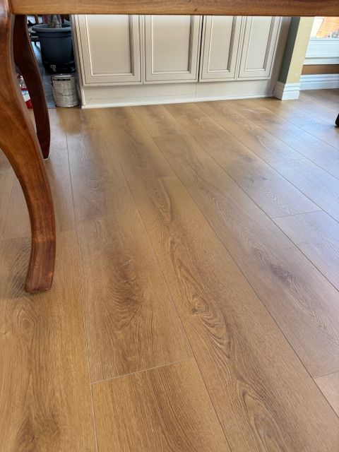 A wooden table is sitting on a wooden floor in a kitchen.