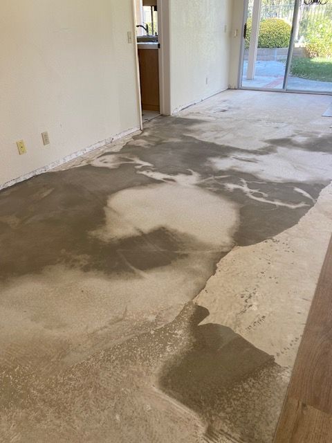 A living room with a concrete floor and a sliding glass door.