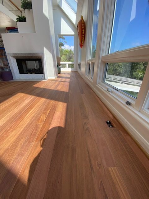 A living room with a wooden floor and lots of windows
