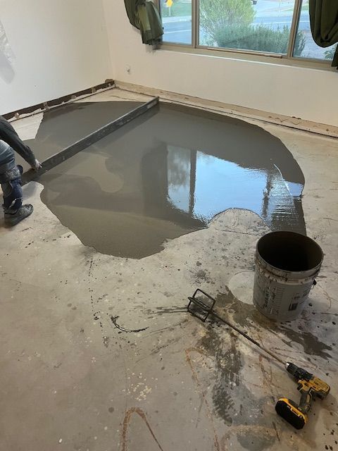 A person is pouring concrete into a hole in the floor.