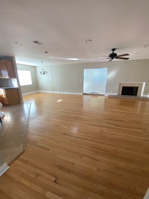 An empty living room with hardwood floors and a ceiling fan.