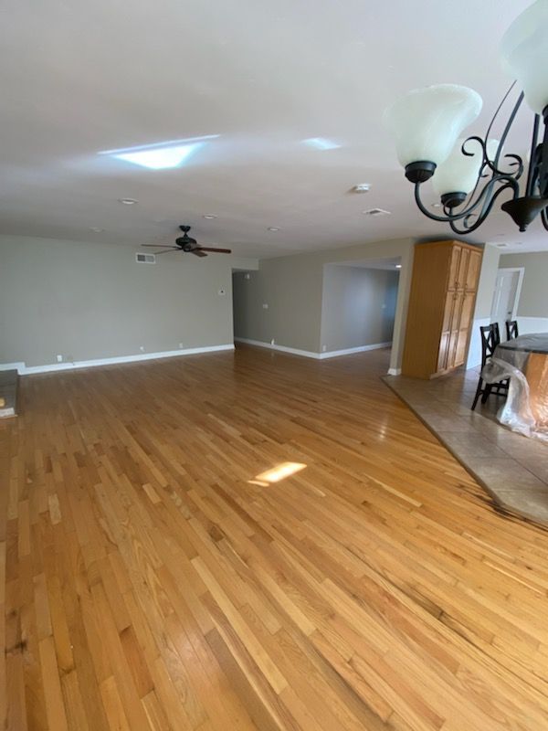 A large empty room with hardwood floors and a ceiling fan.