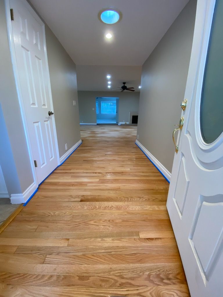 A hallway with hardwood floors and a white door