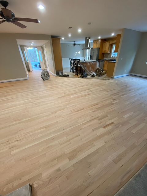 A living room with hardwood floors and a ceiling fan.