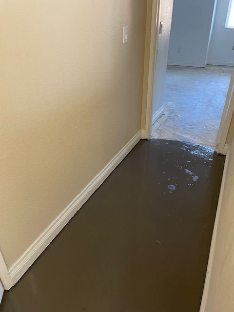 A hallway with a flooded floor and a doorway leading to a room.
