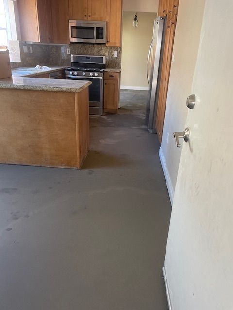 A kitchen with wooden cabinets , stainless steel appliances , a microwave and a refrigerator.