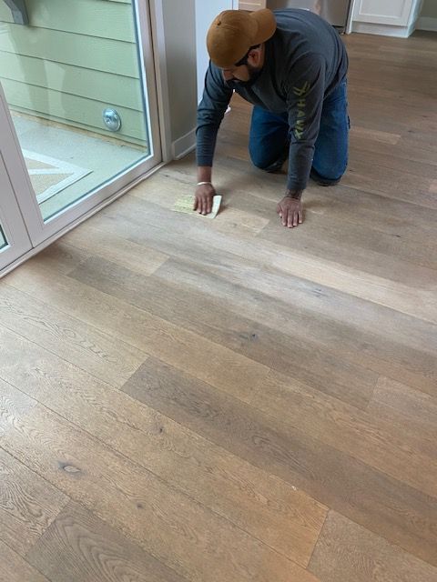 A man is kneeling on the floor cleaning it with a sponge.