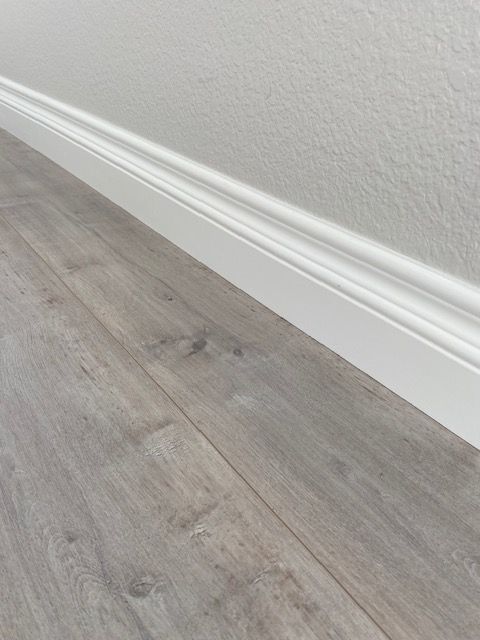 Floor installation with baseboard updates in Carlsbad.