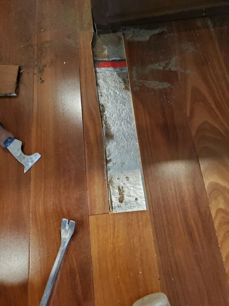 A person is working on a wooden floor with a spatula for flooring repairs in san diego county