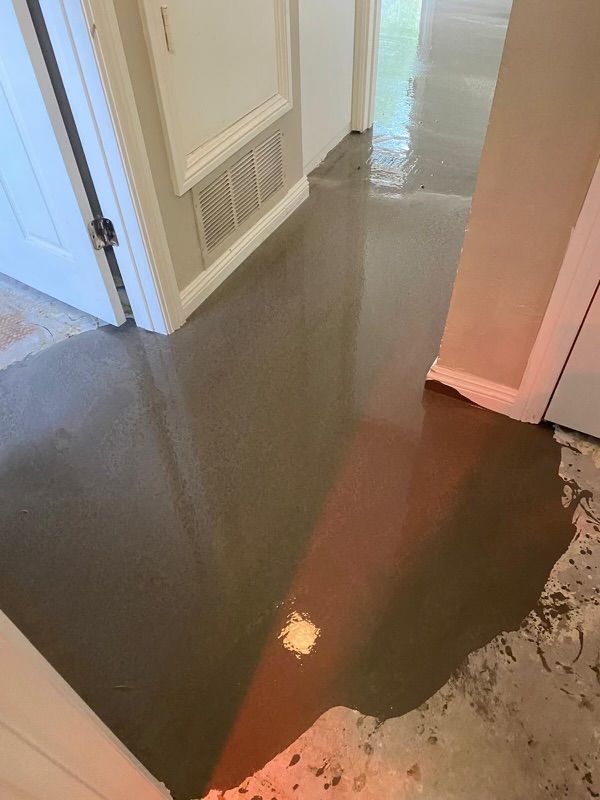 A hallway with a puddle of liquid on the floor.