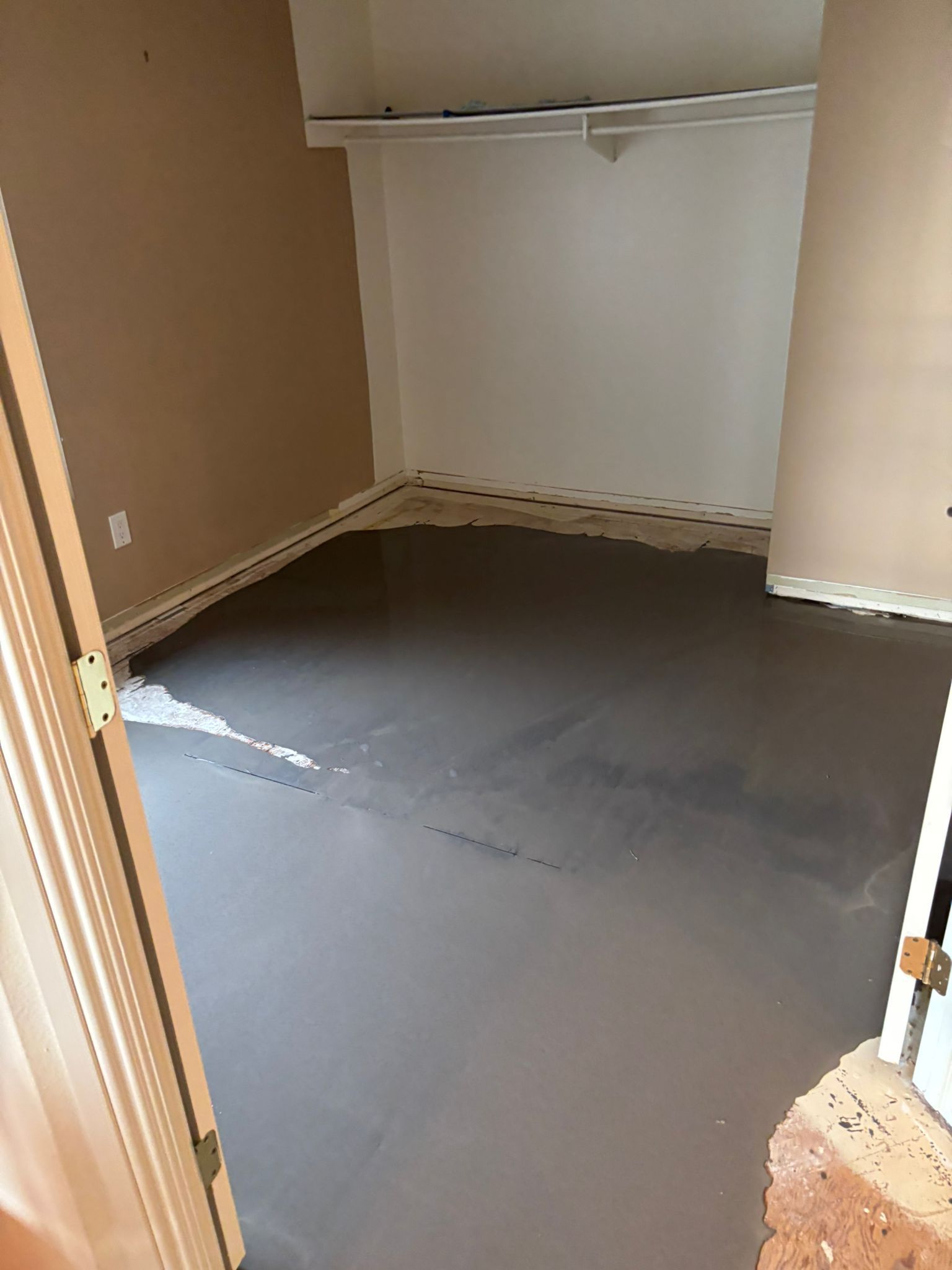 A room with a gray floor and a brick wall
