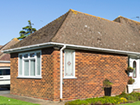 a small brick house with a brown roof and white windows .