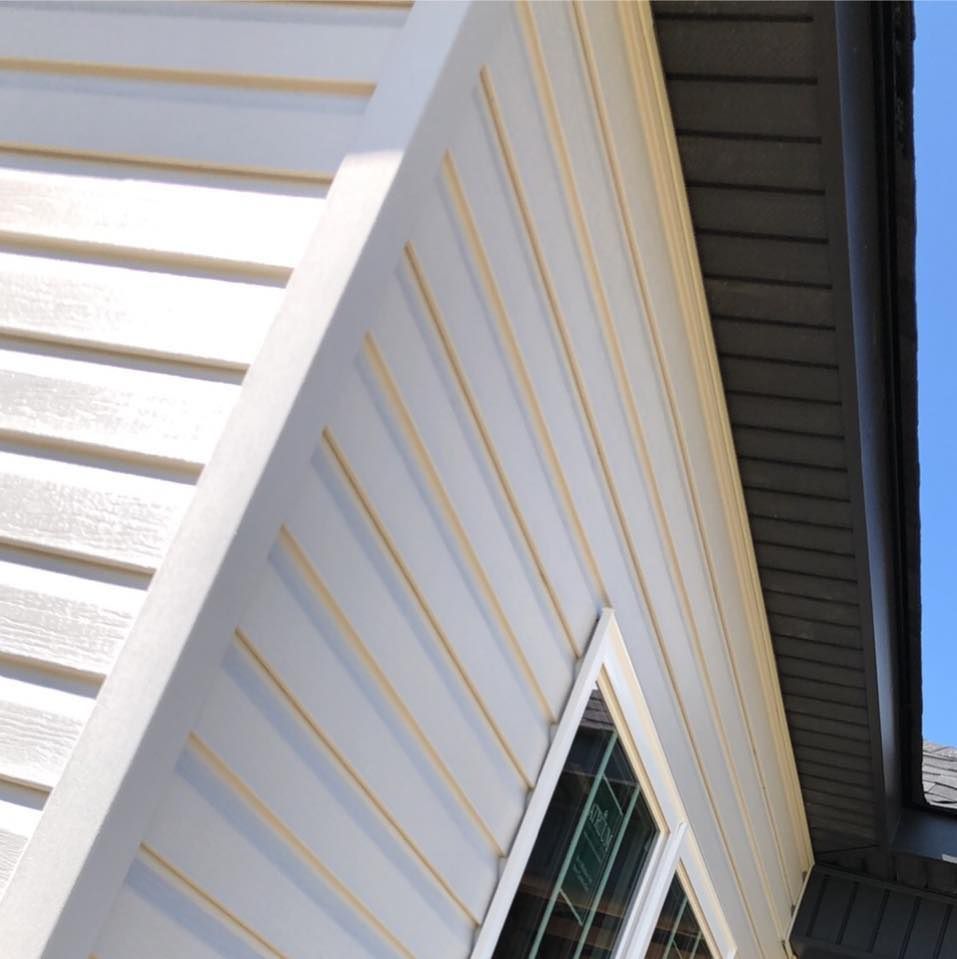 White siding with beige accents and a dark gray roof.