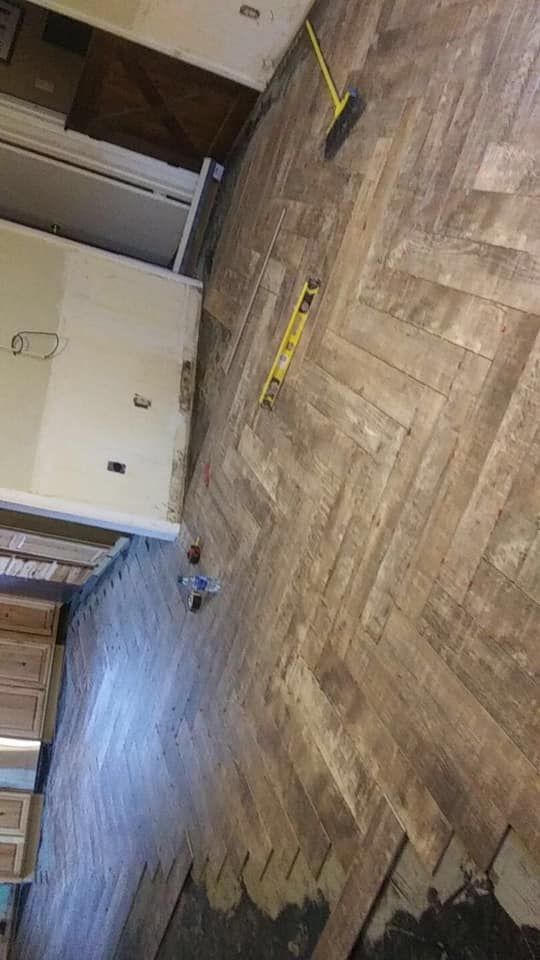 Herringbone wood floor being repaired with tools scattered around.