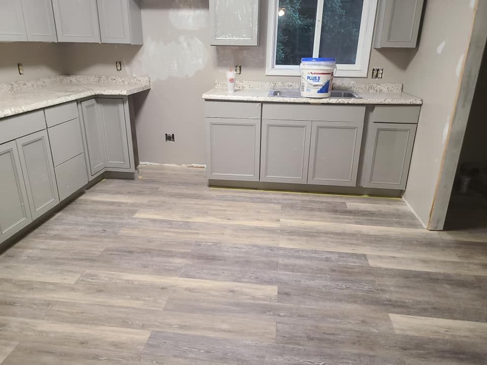Gray kitchen cabinets, light gray countertops, and wood-look flooring.
