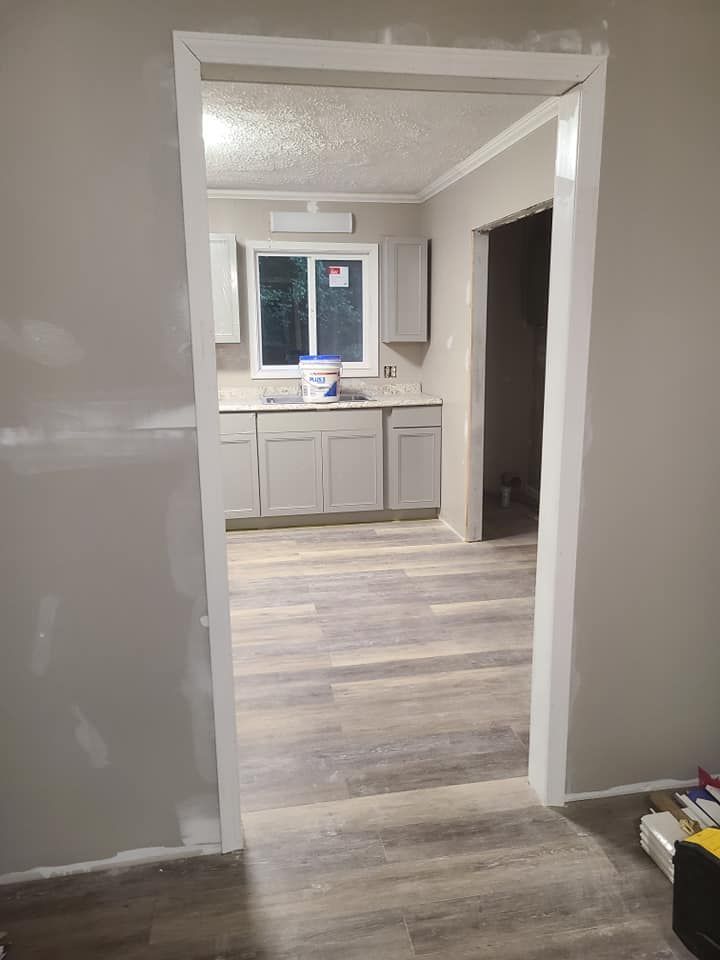 An interior view through a doorway, showing a kitchen with gray cabinets and flooring.