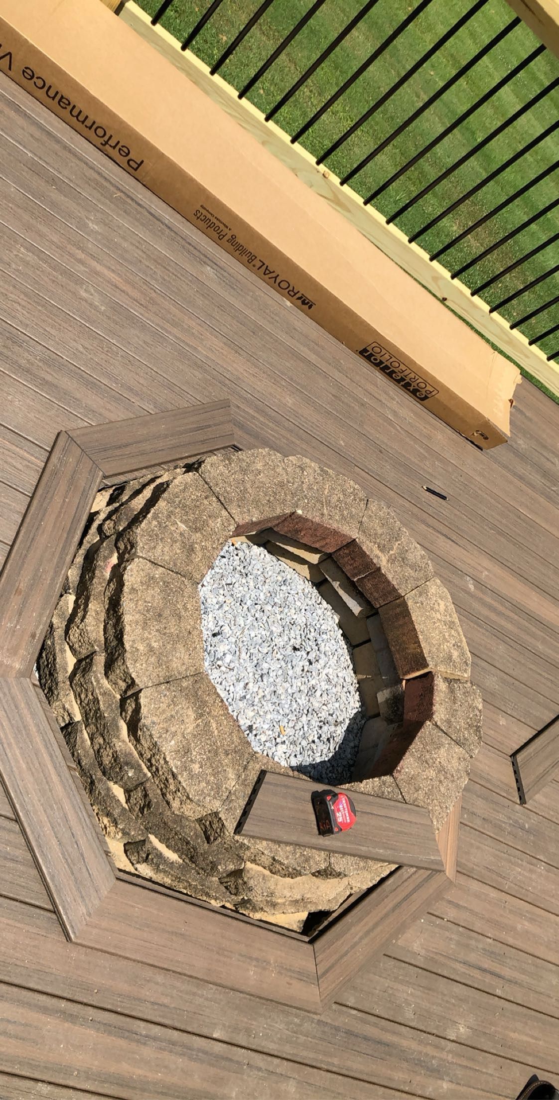 Raised outdoor fire pit built into a wooden deck, surrounded by gravel.