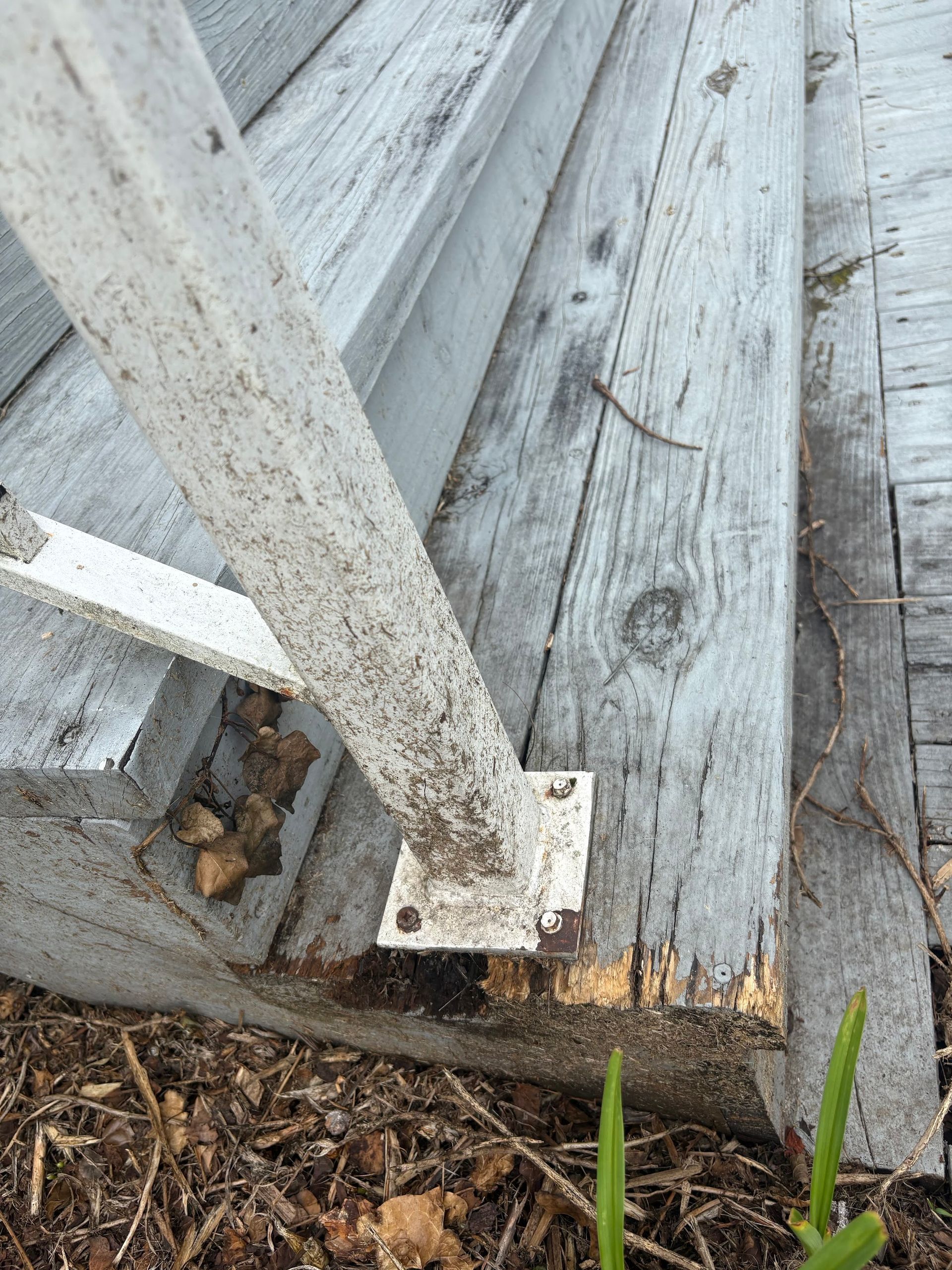 White painted metal railing attached to weathered gray wooden planks.