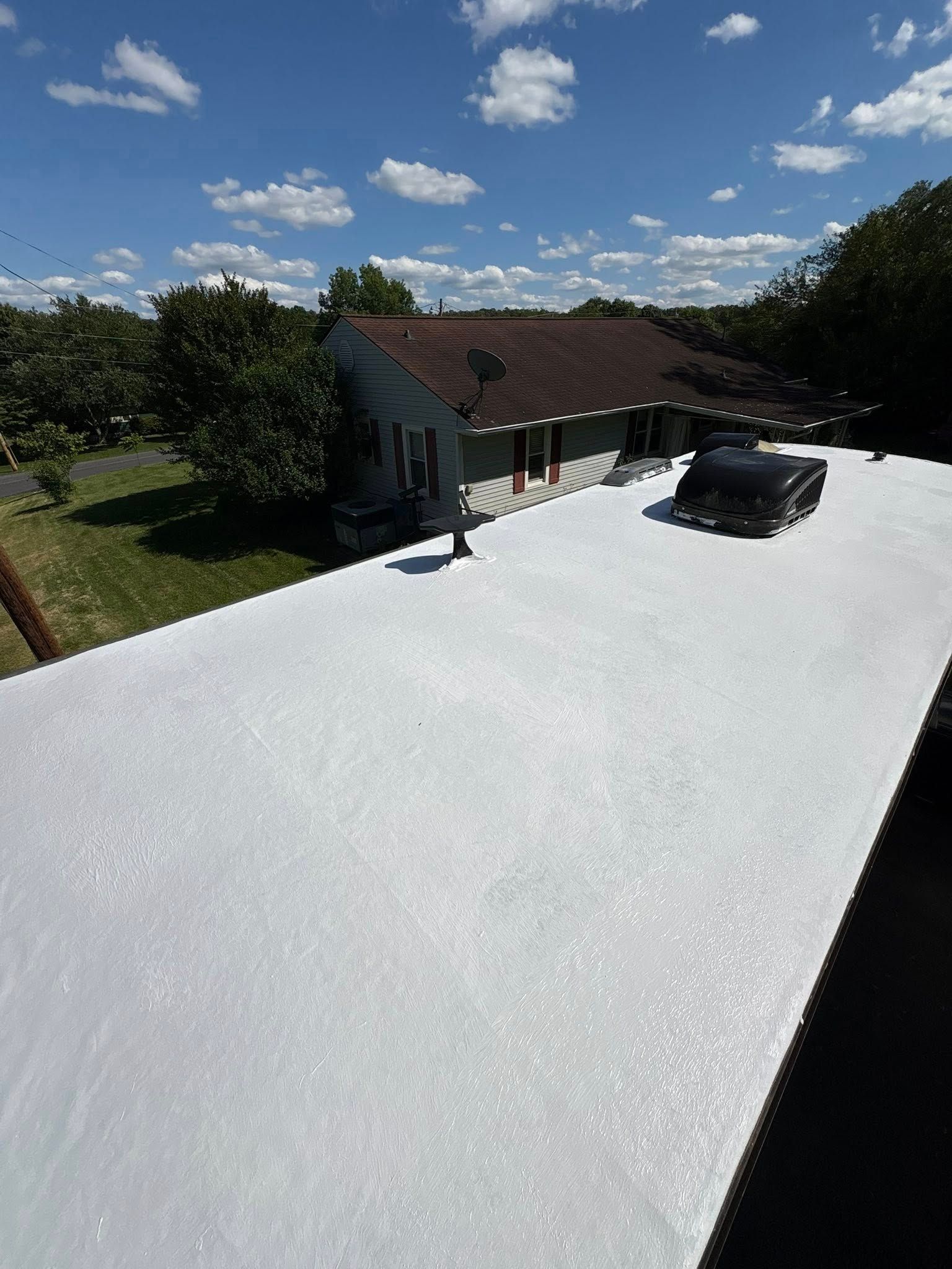 White roof with a building and trees under a blue sky.