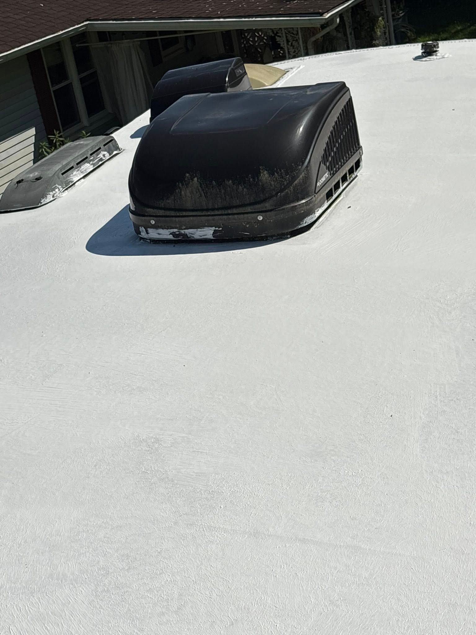 A white roof with black air conditioning units, on a sunny day.
