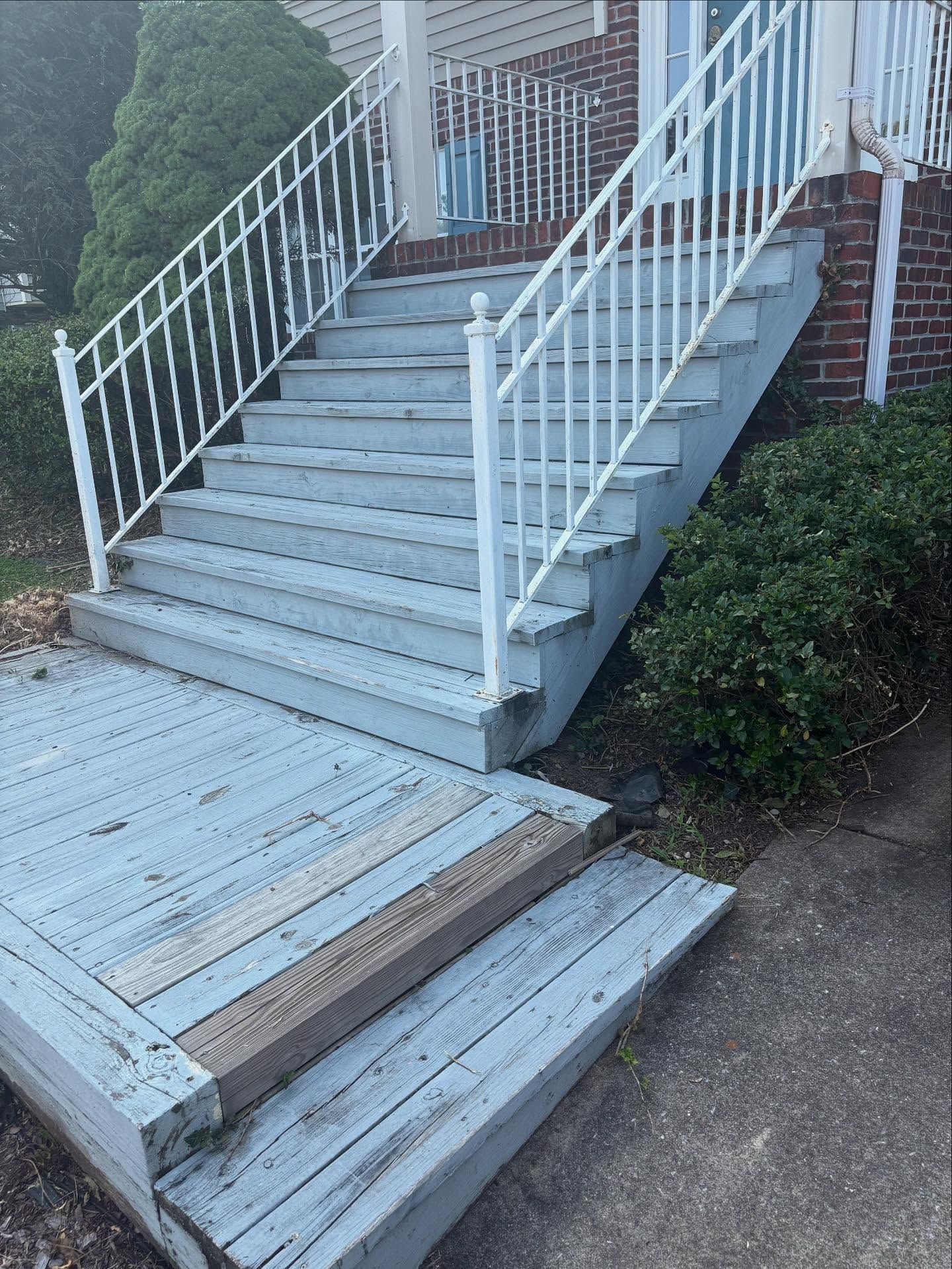 Exterior stairs and porch painted blue-gray with white railings, leading to a brick house.