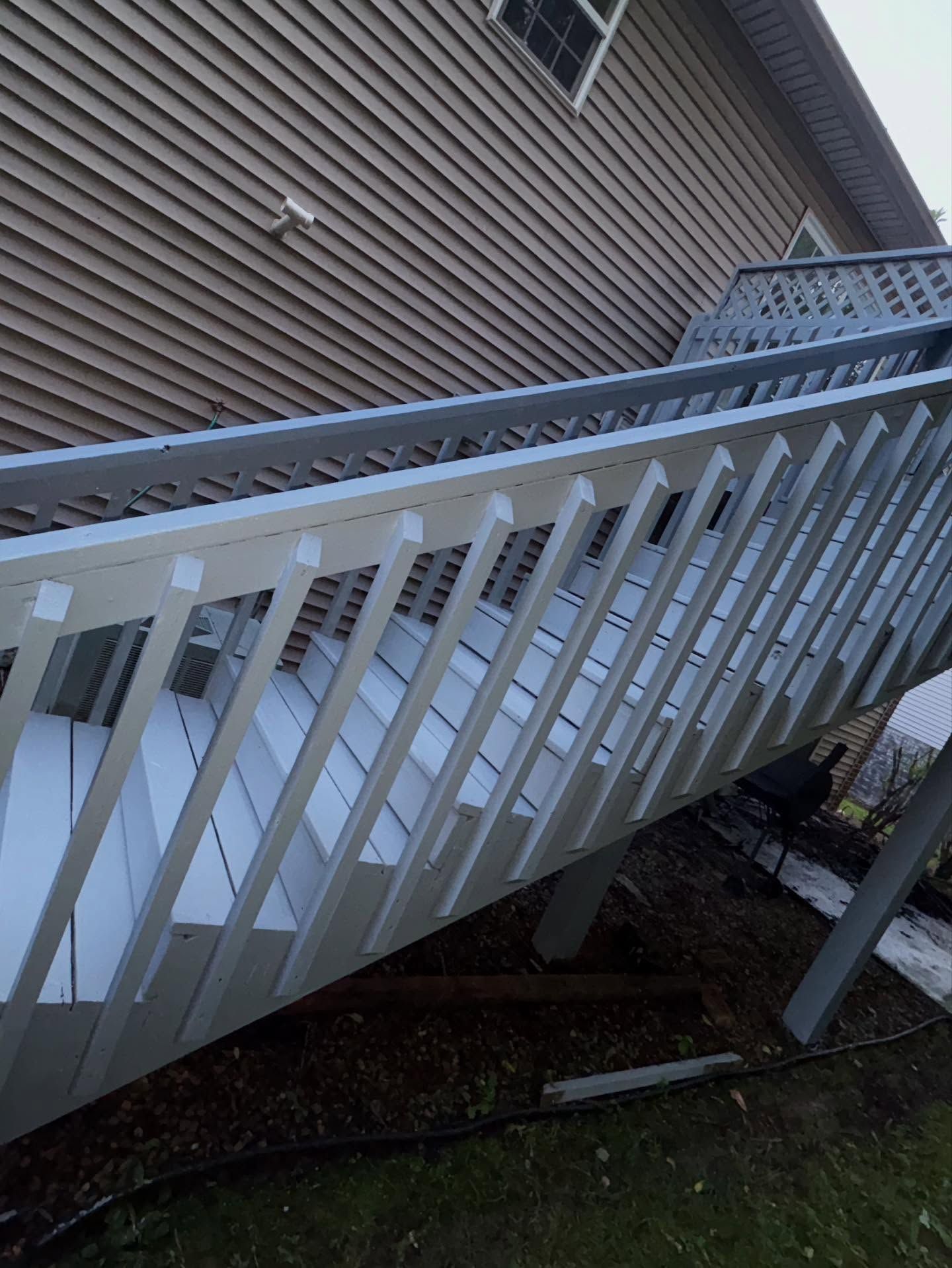 Outdoor staircase with light grey railings and steps, attached to a light brown house.