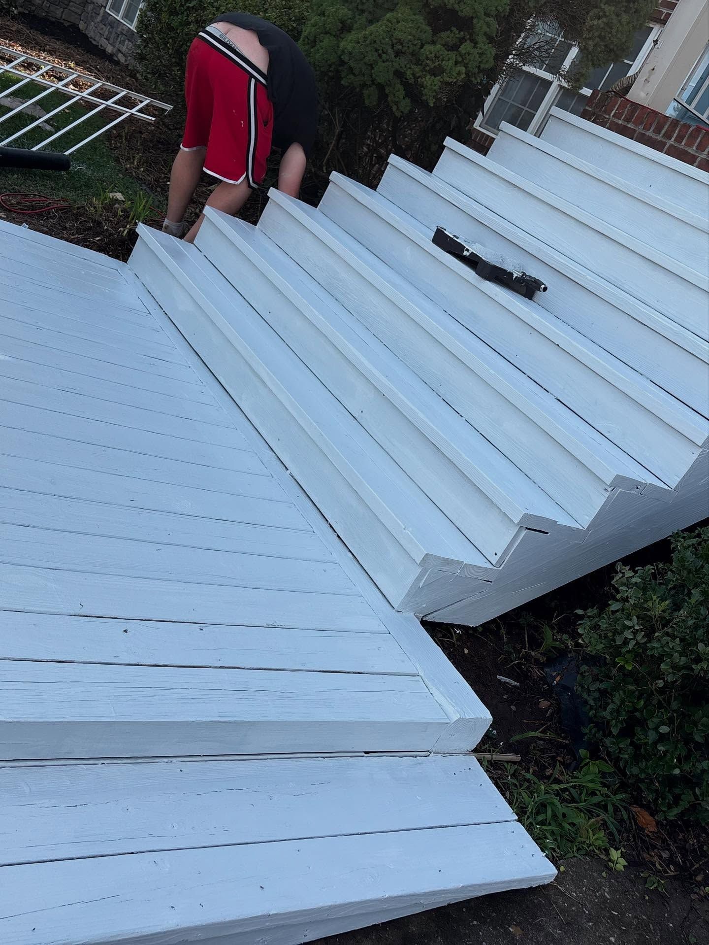 Person working on white painted wooden deck steps.