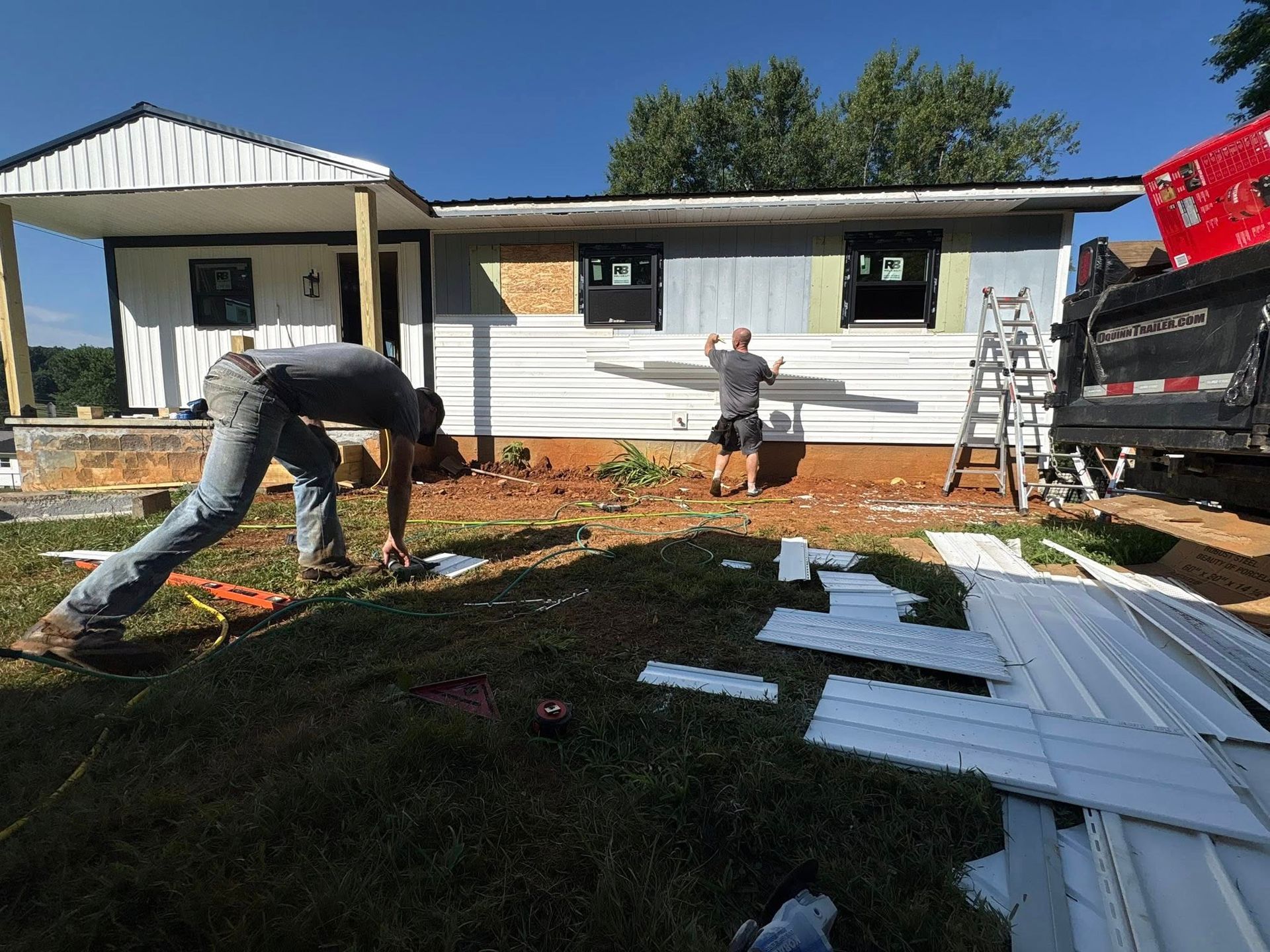 Men installing siding on a house, working outside on a sunny day.