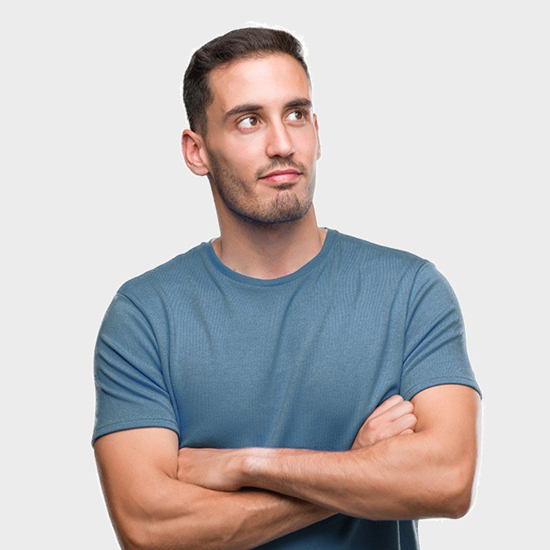 Man in blue shirt with arms crossed, looking up thoughtfully against a white background.