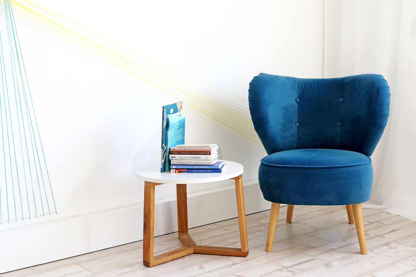 Der blaue Sessel steht neben einem Tischchen. Darauf siehst du mehrere Bücher mit Fachliteratur. 