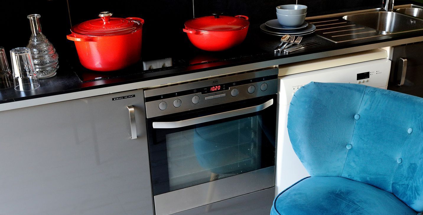 Der blaue Sessel steht vor einem Herd. Auf dem Herd siehst du 2 rote Töpfe. 