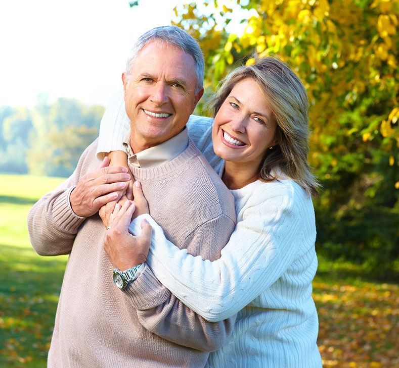 White elderly couple embracing each other at the park