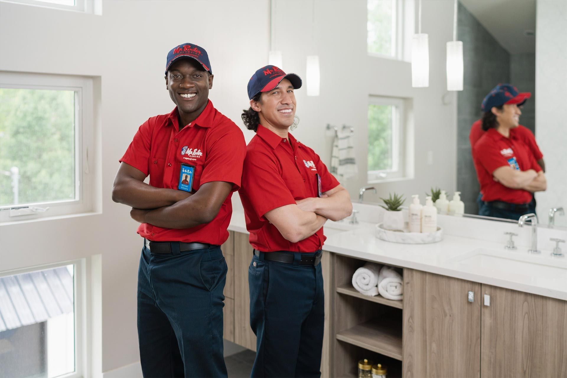 A professional wearing a red uniform and cap shows a tablet screen to a person while standing in a home.