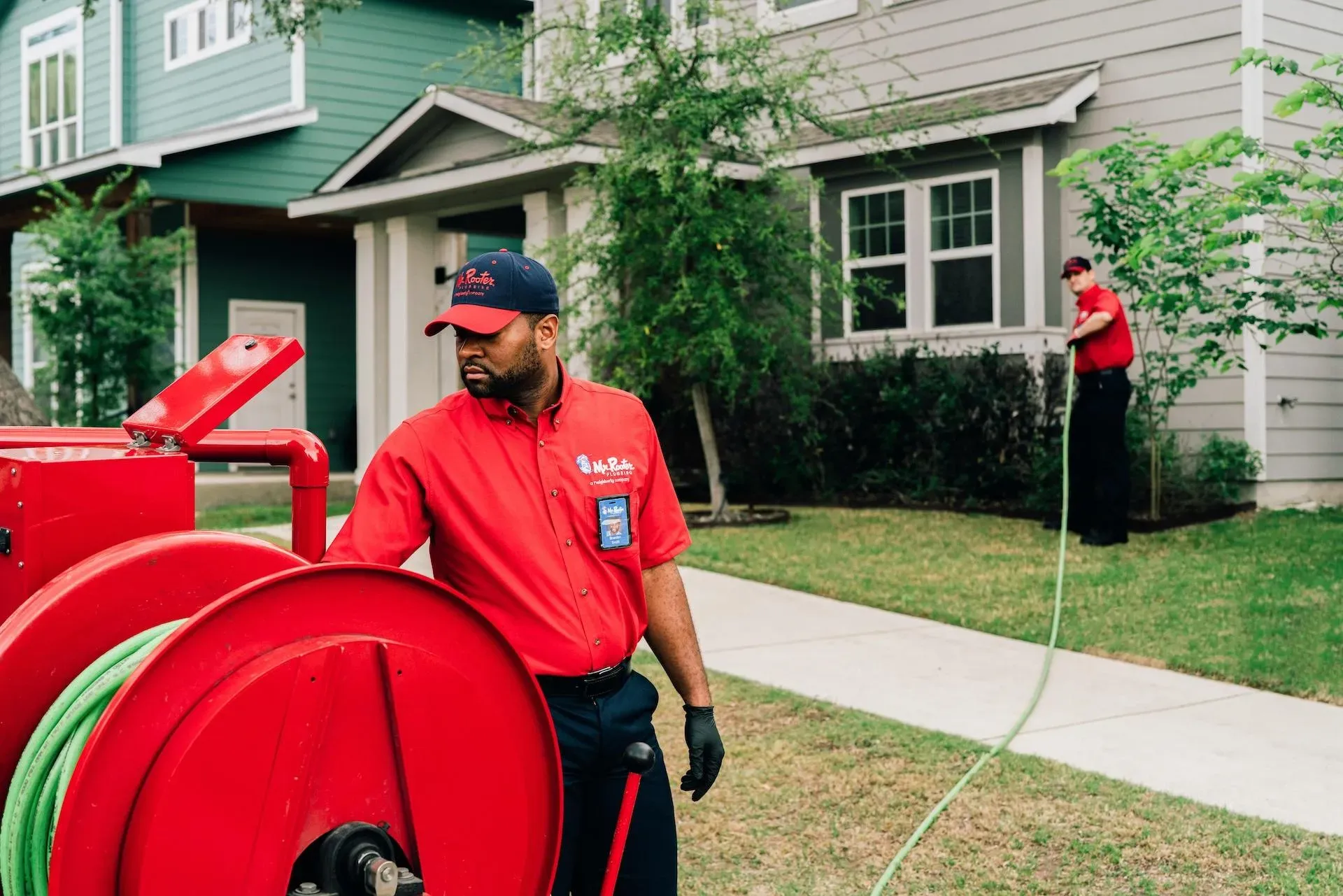 A professional wearing a red uniform and cap shows a tablet screen to a person while standing in a home.