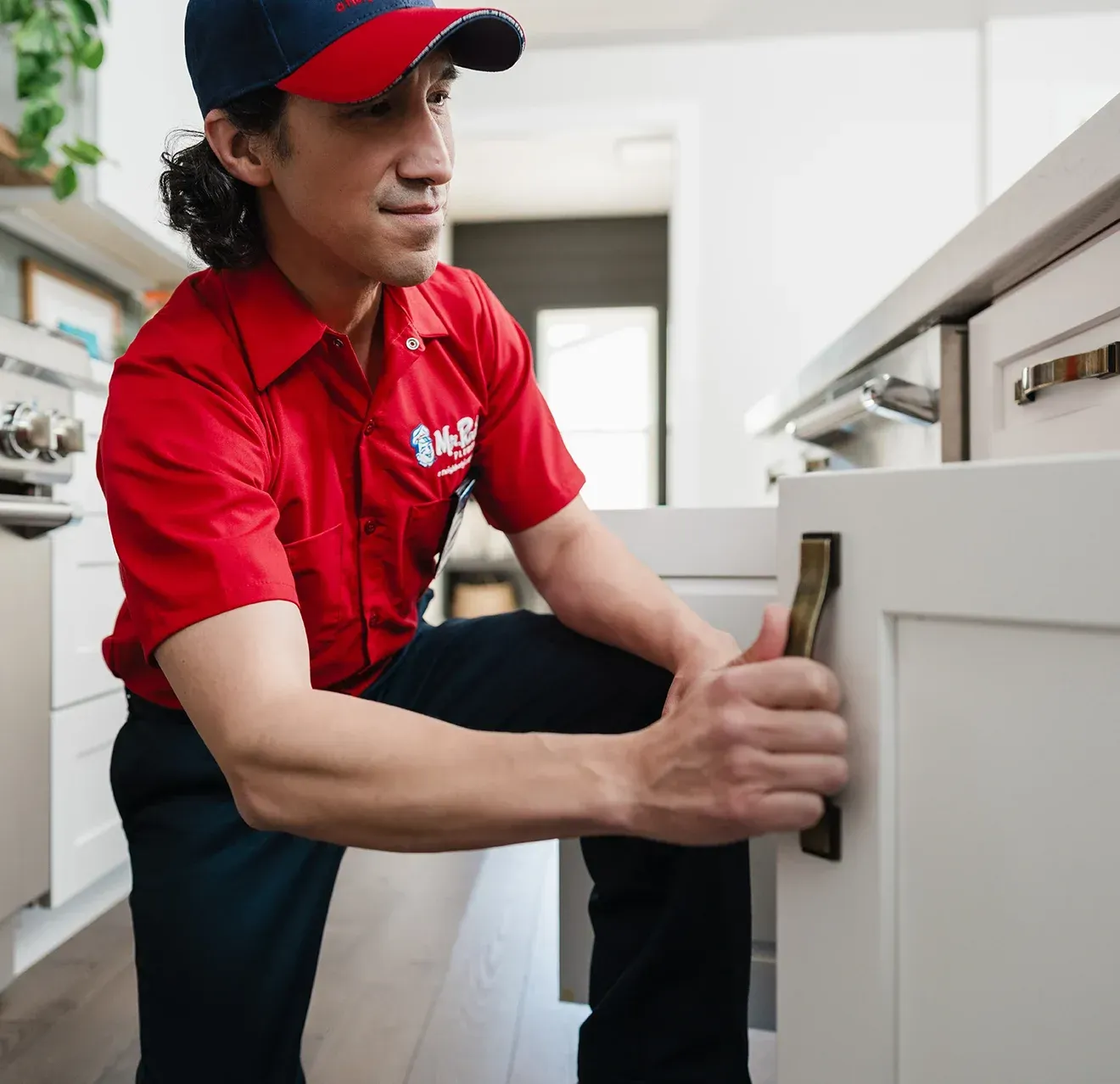 A professional wearing a red uniform and cap shows a tablet screen to a person while standing in a home.