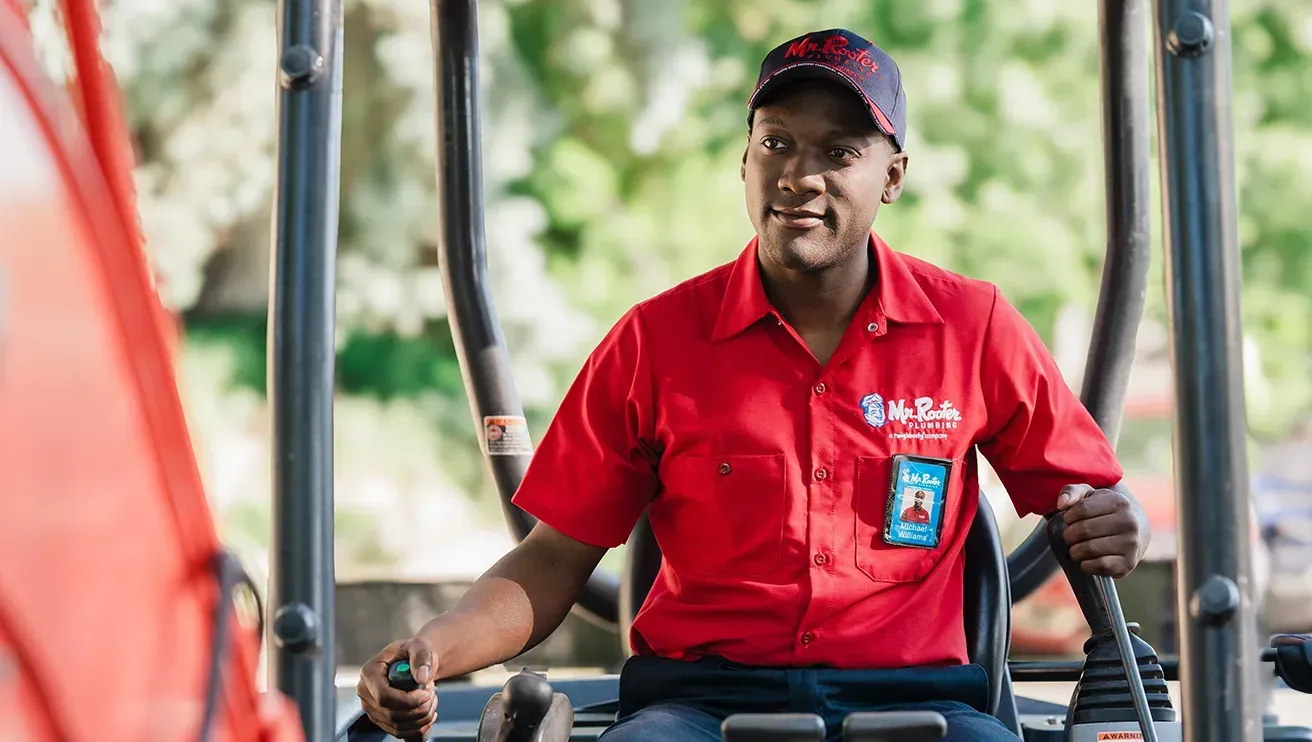 A professional wearing a red uniform and cap shows a tablet screen to a person while standing in a home.