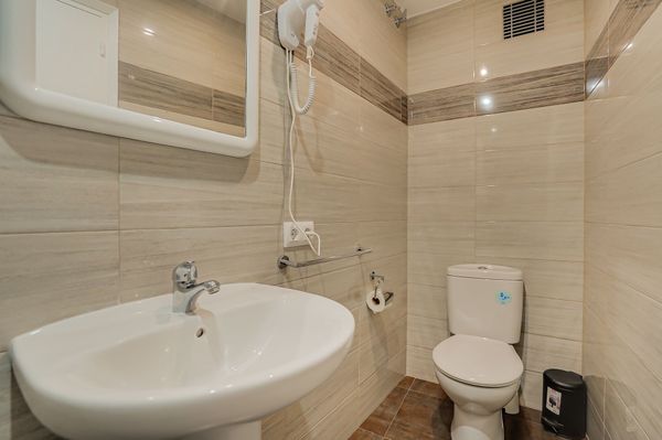 Baño pequeño de color beige con lavabo, inodoro, armario con espejo y paredes alicatadas.